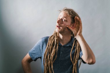 Genç adam sağlam bir arka plan üzerinde bir şey dinlerken