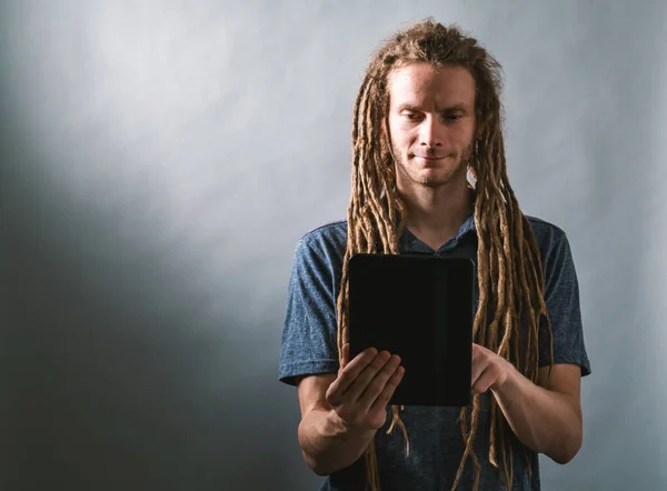 Jovem usando um tablet em um fundo escuro — Fotografia de Stock