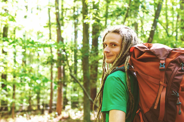 Happy male hiker with backpack trekking through the forest