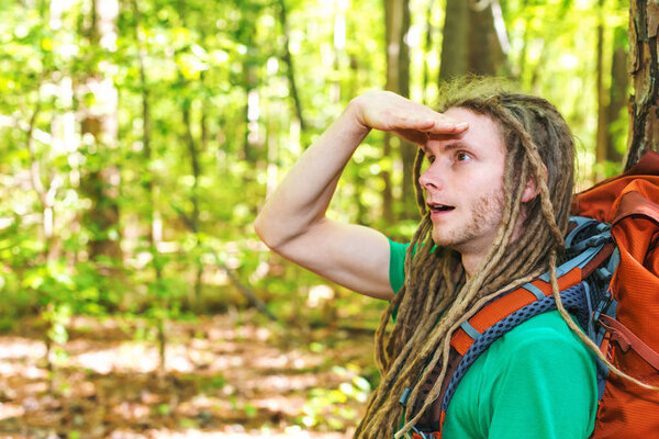 Male hiker with backpack looking at something ahead in the forest