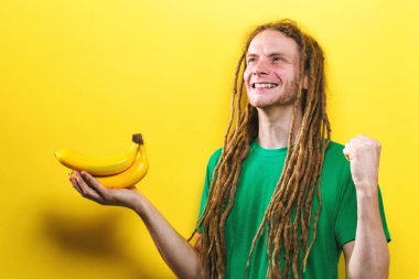 Muz sarı bir arka plan üzerinde tutan mutlu genç adam