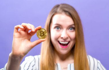 Fiziksel bir bitcoin tutan kadın