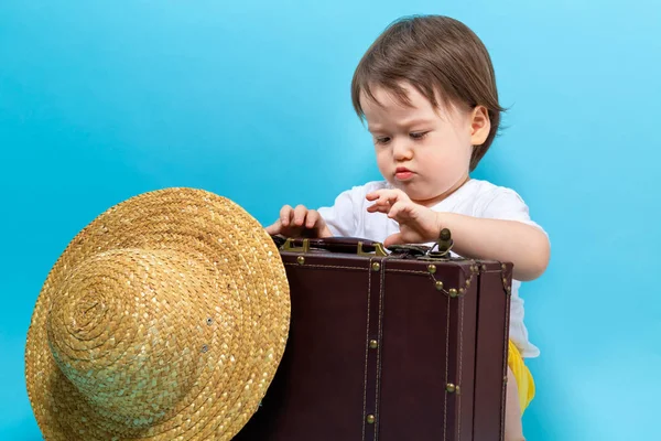 Toddler boy travel theme with a suitecase and a hat — Stock Photo, Image