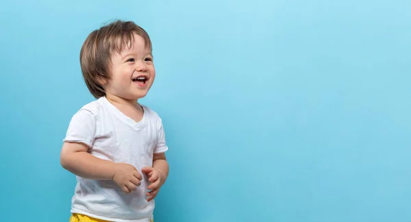 Toddler chłopiec uśmiecha się na niebieskim tle — Zdjęcie stockowe