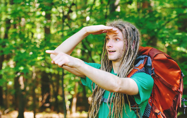 Male hiker with backpack pointing at something ahead in the forest