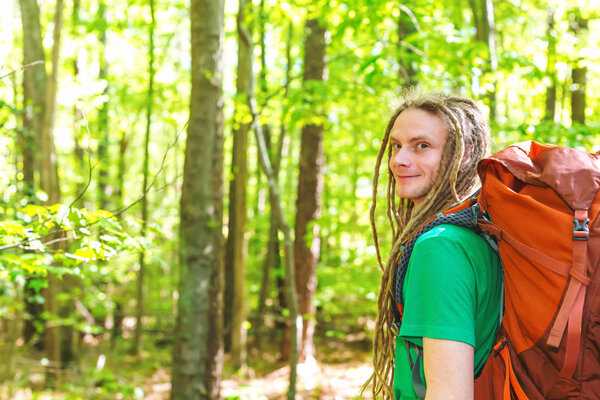 Happy male hiker with backpack trekking through the forest
