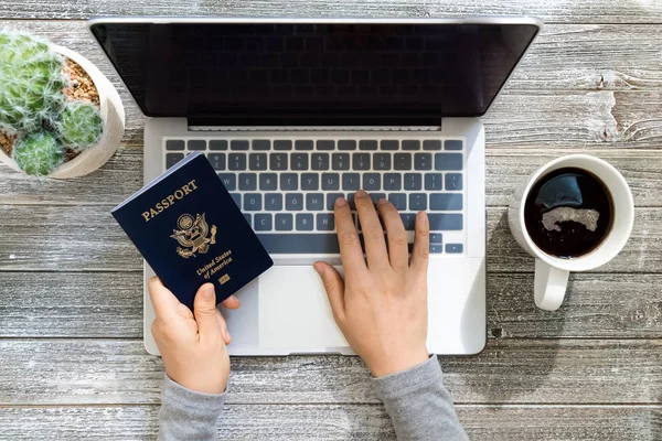 Pessoa segurando um passaporte americano ao usar um laptop — Fotografia de Stock