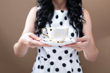 Elinde kahve tutan genç bir kadın.