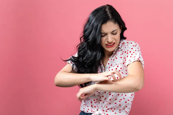 Mujer joven arañándose el brazo con picazón . —  Fotos de Stock