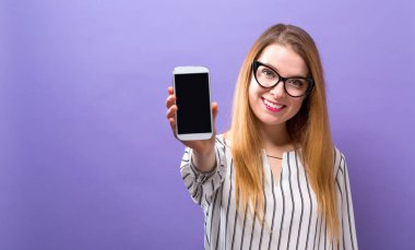 Elinde cep telefonu tutan genç bir kadın.