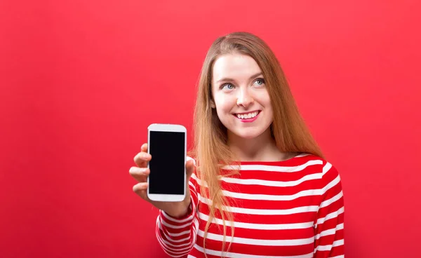 Ung kvinna håller ut en mobiltelefon — Stockfoto