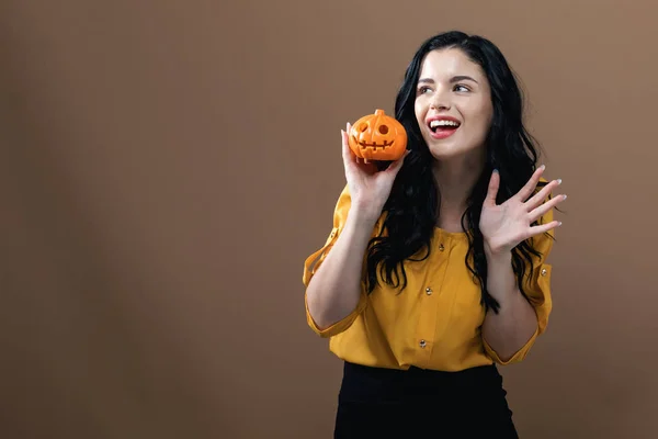 Jonge vrouw met een halloween pompoen — Stockfoto