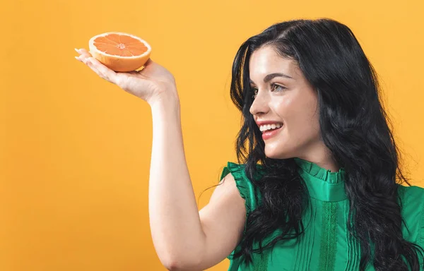 Gelukkig jonge vrouw bedrijf oranje — Stockfoto