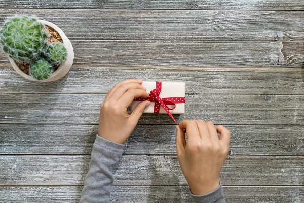 Frau mit einem Geschenkkarton auf einem Holztisch — Stockfoto