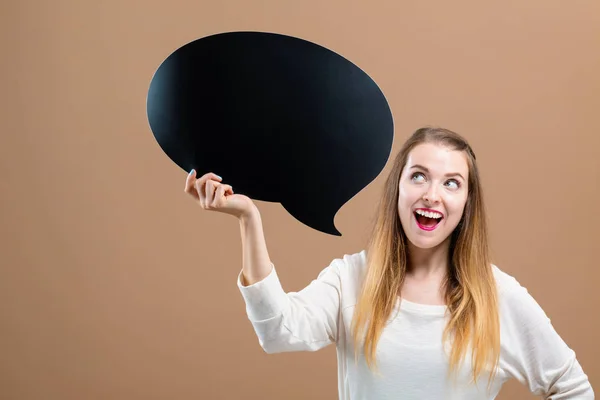 Mujer joven sosteniendo una burbuja del discurso — Foto de Stock