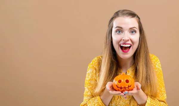 Jonge vrouw met een halloween pompoen — Stockfoto