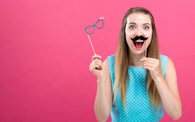 Kağıt bardak ve bıyıklı sopa ile genç kadın