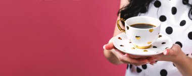 Elinde kahve tutan genç bir kadın.