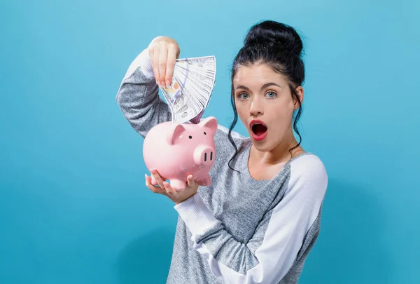 Young woman with a piggy bank with us dollar bills — Stock Photo, Image