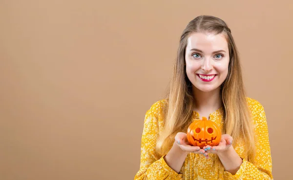 Ung kvinna med en halloween pumpa — Stockfoto