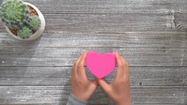 Pembe kalp şeklinde kutu tutan kişi