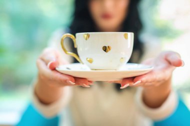 Elinde kahve tutan genç bir kadın.