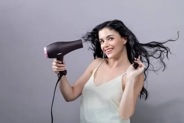 Hermosa joven sosteniendo un secador de pelo — Foto de Stock