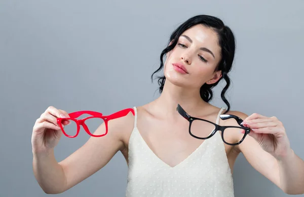 Mladá žena porovnávání dvou oko brýle — Stock fotografie