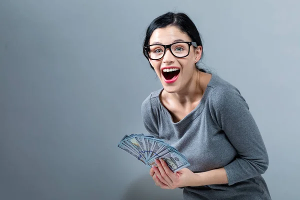 Mujer joven con una pila de dinero en efectivo USD — Foto de Stock