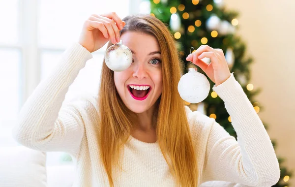 Mujer feliz sosteniendo adornos de Navidad en su casa — Foto de Stock