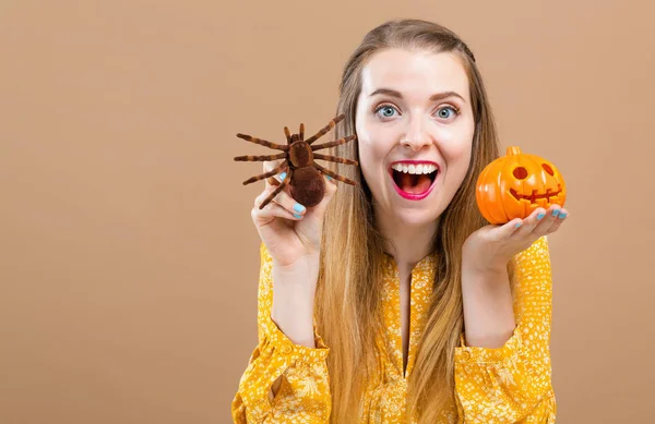 Mujer joven sosteniendo una calabaza de halloween y una araña — Foto de Stock