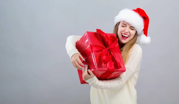 Mladá žena s kloboukem Santa drží dárkovou krabici — Stock fotografie