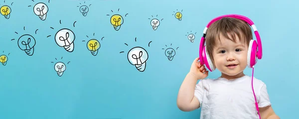 Many light bulbs with toddler boy with headphones — Stock Photo, Image