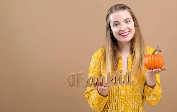 Young woman holding a thankful block and a pumpkin — Stock Photo, Image