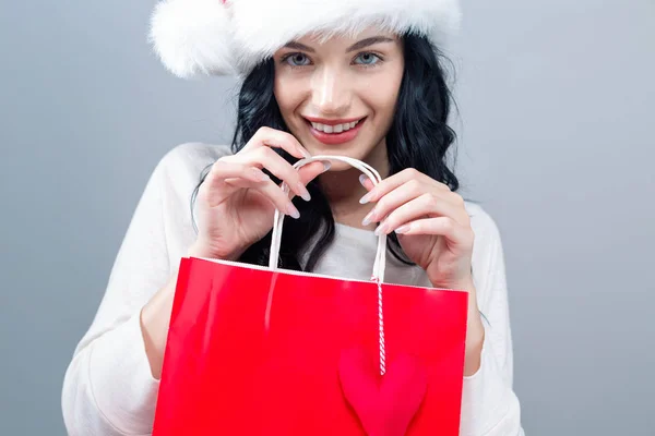 Happy young woman with santa hat holding a shopping bag — Stock Photo, Image