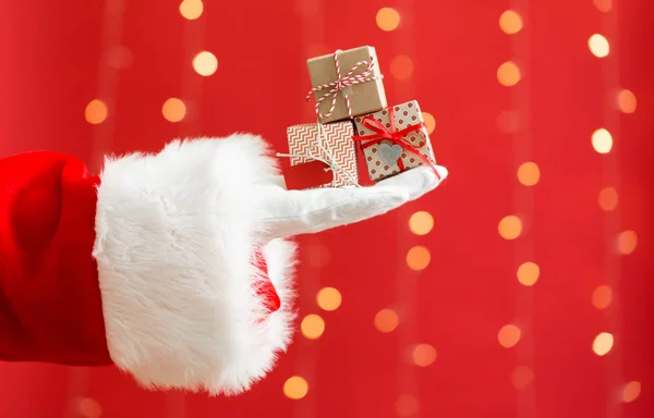 Santa segurando pequenas caixas de presente de Natal — Fotografia de Stock