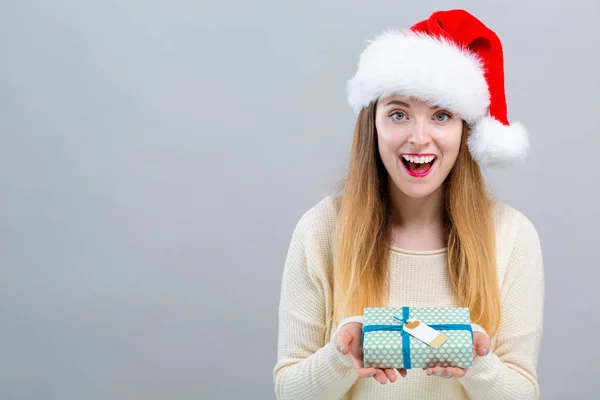 Mladá žena s kloboukem Santa drží dárkovou krabici — Stock fotografie