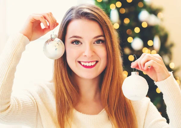 Happy woman holding Christmas ornaments in her house — Stock Photo, Image