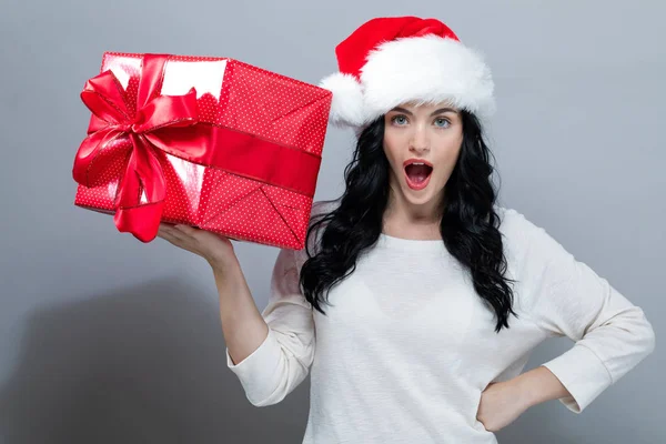 Jonge vrouw met kerstman hoed met een geschenkdoos — Stockfoto