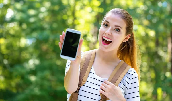 Giovane donna che tiene fuori uno smartphone — Foto Stock