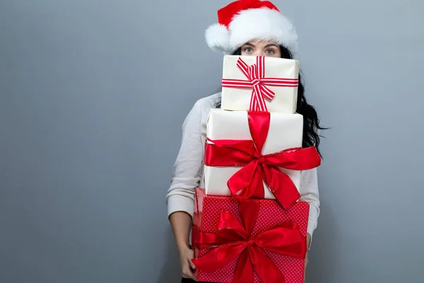 Giovane donna con cappello di Babbo Natale contenente scatole regalo — Foto Stock