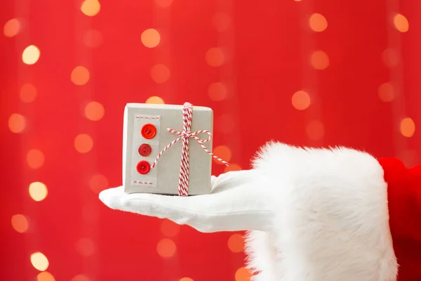 Santa segurando um pequeno presente de Natal — Fotografia de Stock