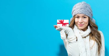 Genç bir kadın elinde Noel hediyesi tutuyor.