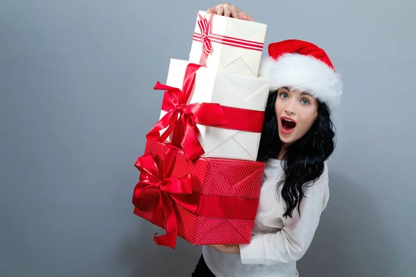 Młoda kobieta w kapeluszu Mikołaja trzyma pudełka z prezentami — Zdjęcie stockowe