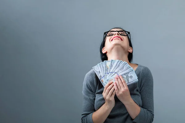Mujer joven con una pila de dinero en efectivo USD — Foto de Stock