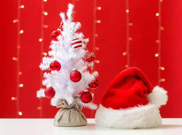 Small white christmas tree with a Santa hat — Stock Photo, Image