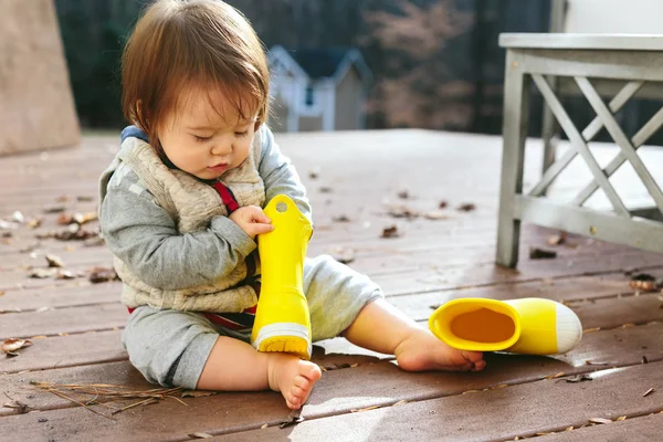 Menino brincando com suas botas de chuva berrante — Fotografia de Stock