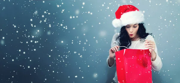 Happy young woman with santa hat holding a shopping bag — Stock Photo, Image