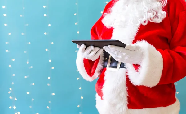 Santa segurando um computador tablet — Fotografia de Stock