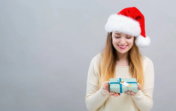 Mujer joven con sombrero de Santa sosteniendo una caja de regalo —  Fotos de Stock